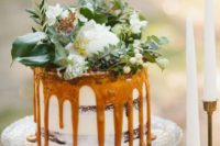 21 a caramel drizzle wedding cake with lush greenery and white blooms on top for a garden or woodland wedding