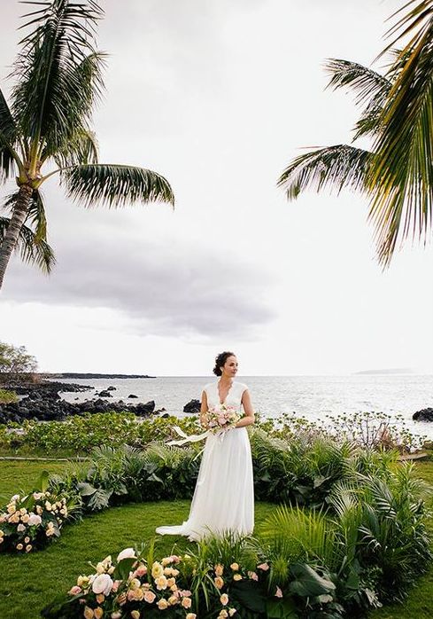 a lush tropical wedding arch of palm leaves and blush blooms lets enjoy a seascape