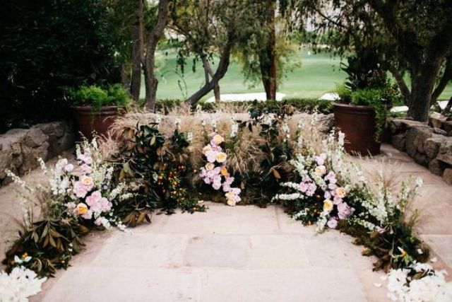 a textural wedding altar of various herbs, leaves, blush and white blooms created on a terrace looks very romantic