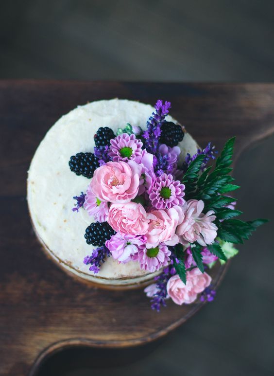 a vanilla lavender naked cake with pink and purple blooms and blackberries
