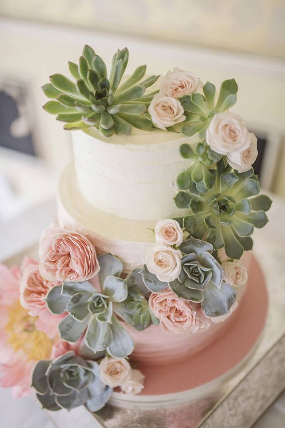 an ombre wedding cake with blush blooms and succulents for decor