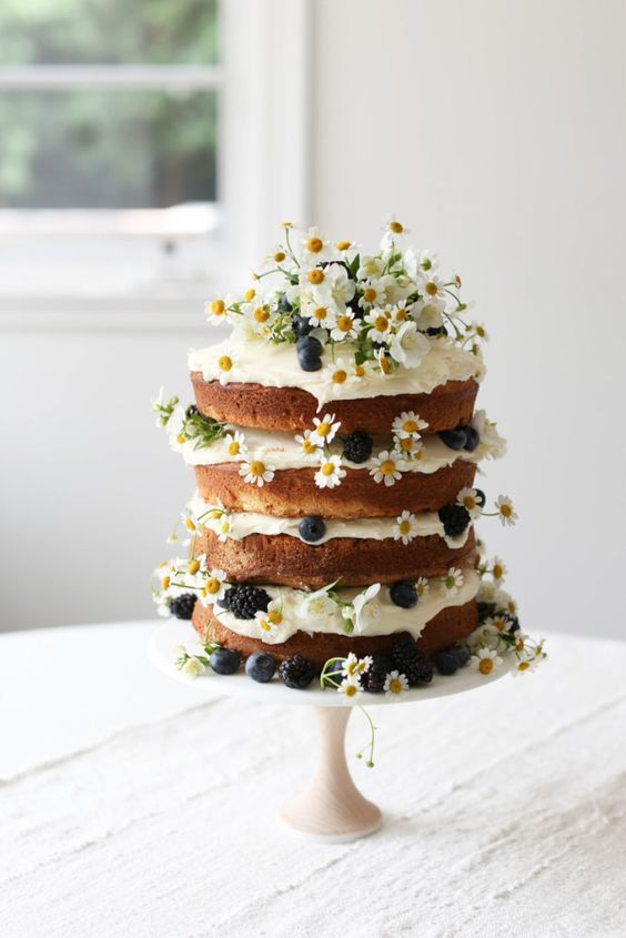 a vanilla naked layer cake with blackberries, blueberries and daisies for a summer garden shower