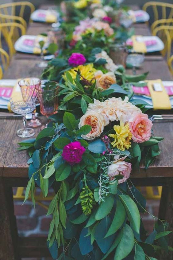 a super lush greenery table runner with yellow, blush and fuchsia flowers is a bold idea for summer