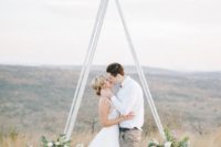 25 a white triangle wedding arbor with lush greenery and large blooms at the base looks very eye-catchy