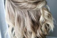a beautiful blonde half updo with a bump on top and a twisted element and waves down is a stylish solution