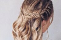 a boho wedding half updo on medium hair, with a large fishtail braid on one side and waves down is a stylish solution