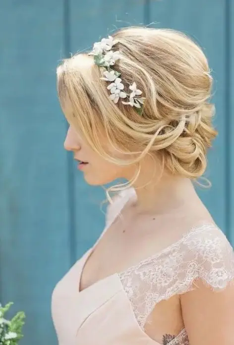 a girlish wavy low updo with a bump and some waves down plus a floral crown looks amazing