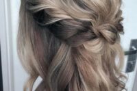 a medium half updo with blonde balayage, a braided halo and a bump and waves down is a timeless solution