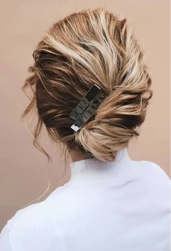a simple and casual wedding hairstyle - a low updo with twisted hair and a volume on top, with locks framing the face