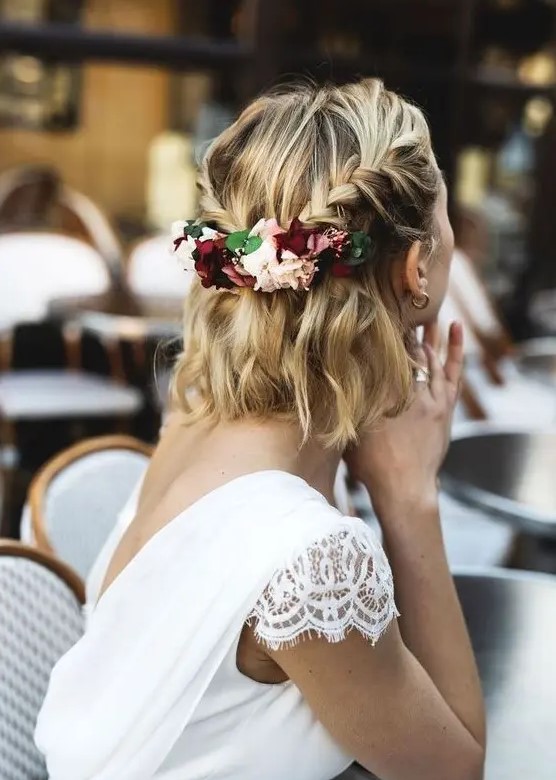 a wavy half updo with two braids secured with fresh flowers and greenery is a chic idea