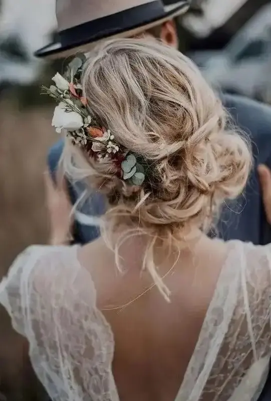 messy and loose wedding low updo with waves and locks down and with a floral accent - neutral and blush blooms and greenery