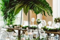 02 a tall wedding centerpiece with lush tropical greenery and some matching leaves at the base