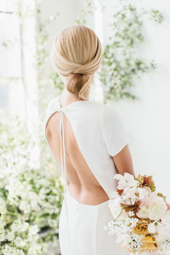 a sleek minimalist twisted low updo with a sleek top is ideal for a minimalist bride