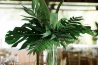 04 a modern tropical leaves wedding centerpiece in a clear glass vase for a cheerful feel