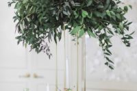 05 a tall centerpiece on a gold stand with lush greenery is an elegant modern idea