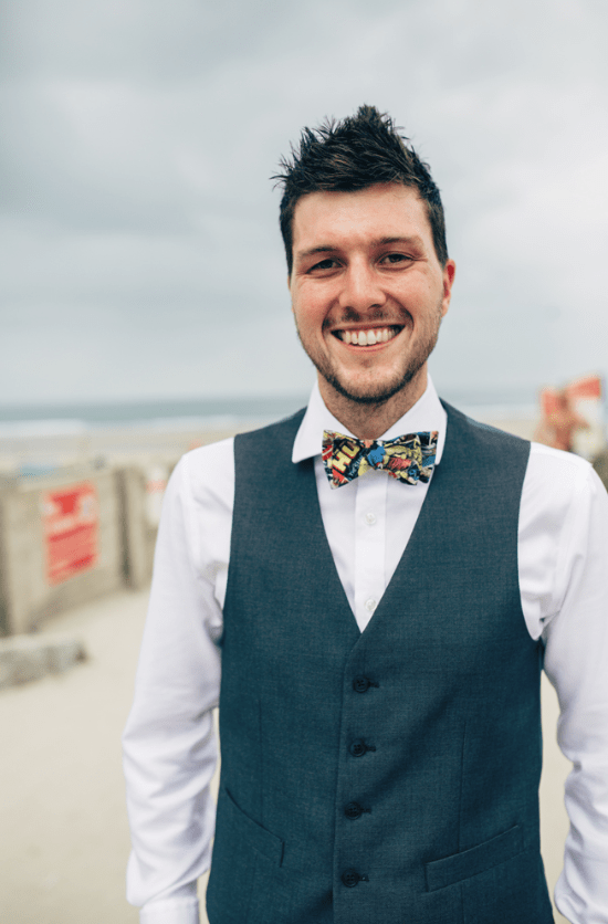 The groom was rocking a grey suit with a vest, a colorful bow tie and colorful socks
