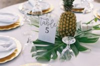 06 a tropical wedding centerpiece made of a large tropical leaf and a pineapple, you won’t need more