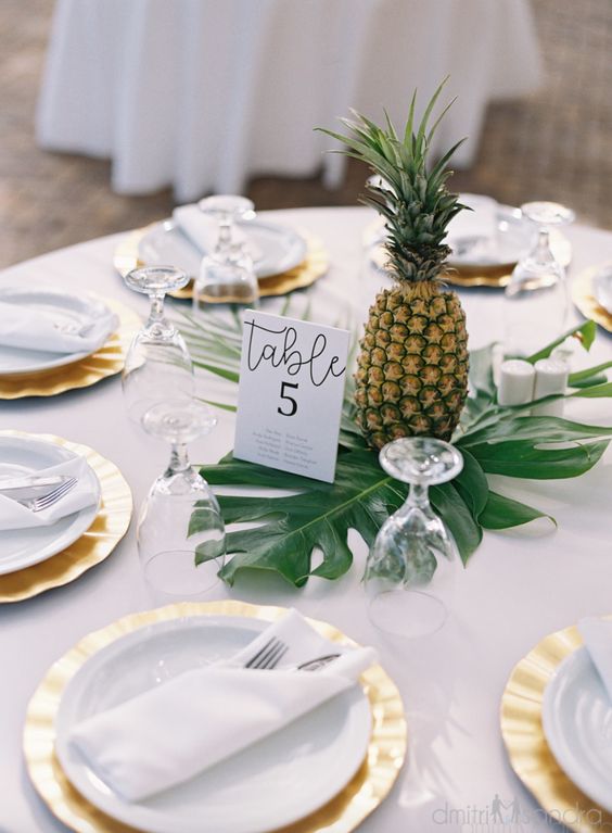 a tropical wedding centerpiece made of a large tropical leaf and a pineapple, you won't need more