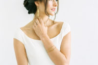 07 a low twisted bun hairstyle with a sleek top and some bangs is a chic and refined idea for a minimalist wedding