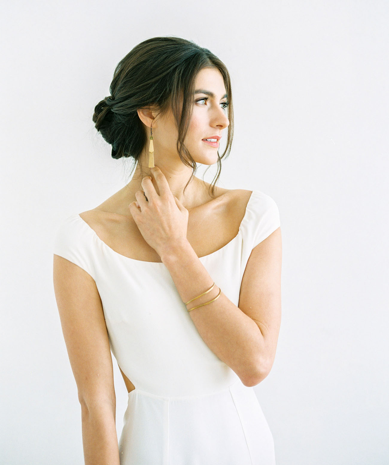 A low twisted bun hairstyle with a sleek top and some bangs is a chic and refined idea for a minimalist wedding