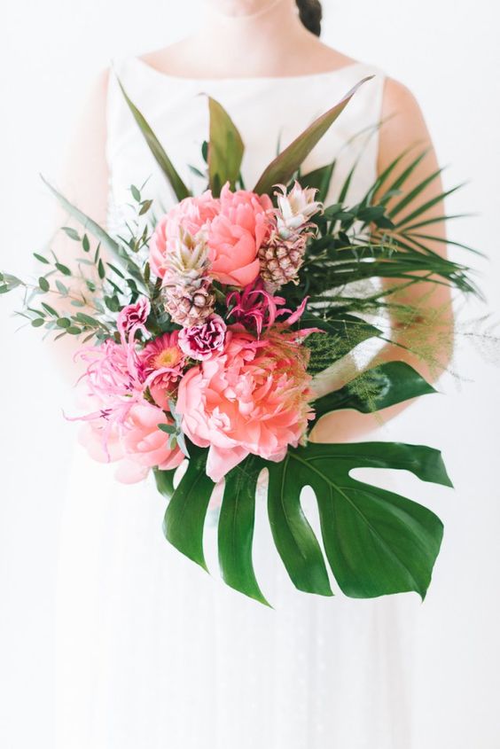 a tropical bouquet with oversized pink blooms, fuchsia flowers, little pineapples and tropical leaves