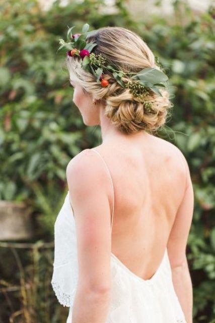 braids woven into a bun and  finished with a floral crown of eucalyptus and little blooms
