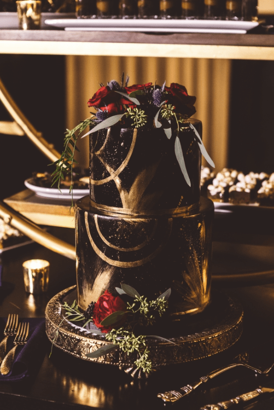 The wedding cake was a black and gold with patterns, topped with thistles and red roses for an ultimate dark romance look