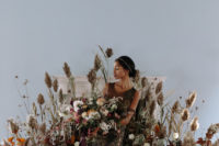 09 This oversized semi circular flower and herb altar was a perfect fit for the shoot, and the black and gold sheath wedding dress strikes at once