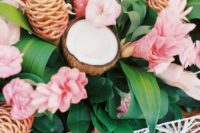 09 a lush tropical table runner ith leaves, pink blooms and coconuts looks very exotic