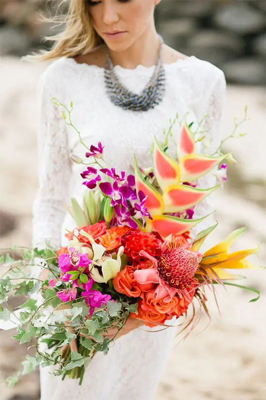 a unique bouquet with greenery, fuchsia, orange and red blooms and a catchy dimension