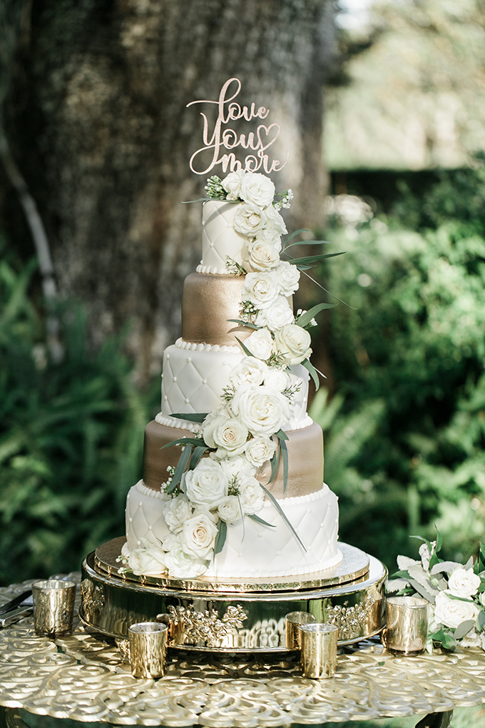 The wedding cake was a gold and white one topped with white ross and a calligraphy topper