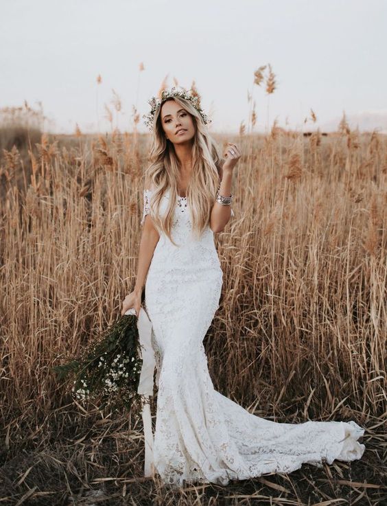 a lace off the shoulder mermaid wedding dress with a small train and a floral crown for a summer boho bride