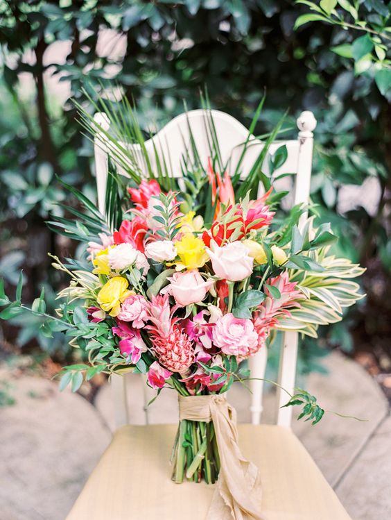 a tropical bouquet with yellow, pink and fuchsia blooms, greenery and tiny pink painted pineapples