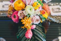 12 a chic tropical wedding centerpiece with a large leaf and bold blooms in pink, yellow and orange