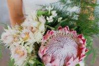 12 a creative and textural bouquet with a king protea, blush and ivory blooms plus ferns for a unique look