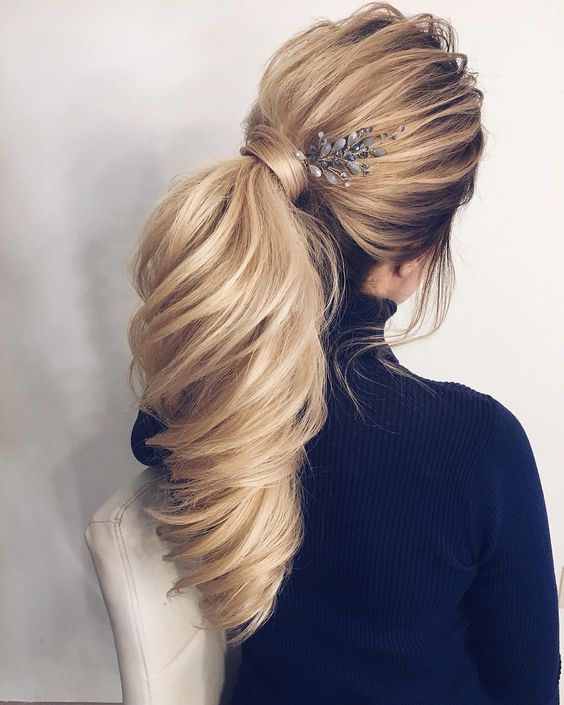a gorgeous  dimensional ponytail with wispy bangs, curls and a cute rhinestone hairpiece on one side
