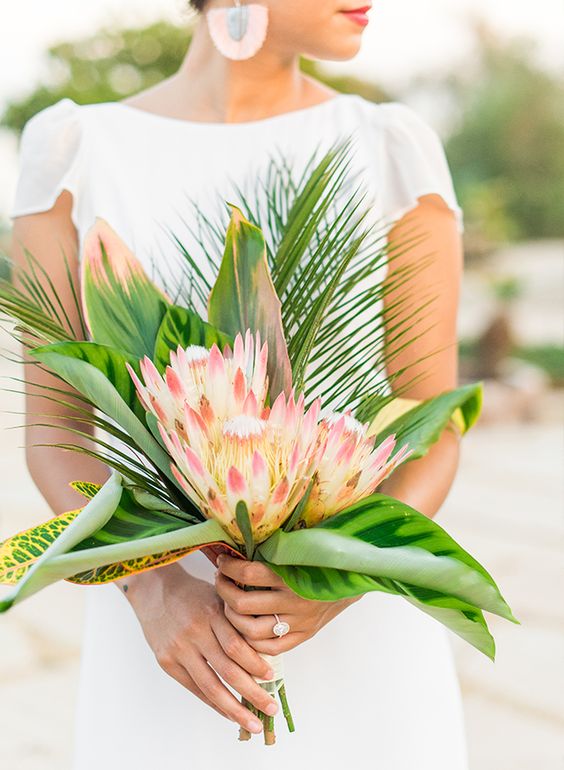 a simple and chic tropical bridal bouquet with three king proteas and tropical leaves