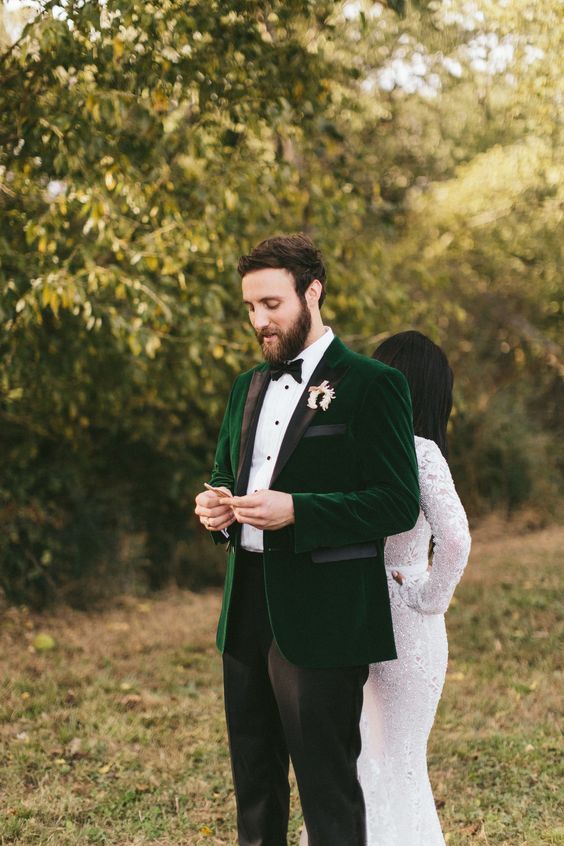 an emerald velvet jacket with black touches, black pants, a bow tie and a white shirt with black buttons