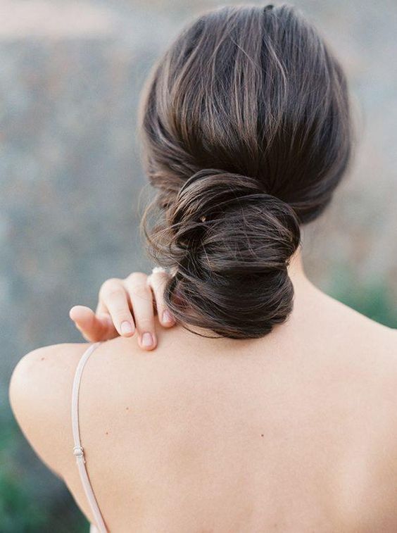 a very low and wavy chignon hairstyle with a volume on top for a modern but very elegant look