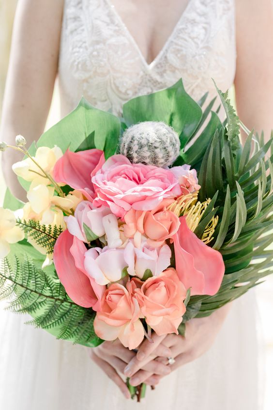 a chic bouquet with yellow and pink blooms, ferns, tropical leaves and even a cacti