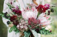 17 a lush and bold wedding bouquet with king proteas, burgundy and plum blooms and bold leaves for a fall boho bride