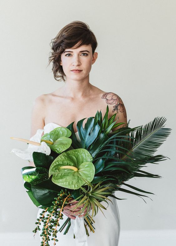 a chic textural and domensional bouquet with large tropical leaves, cascading greenery and orchids