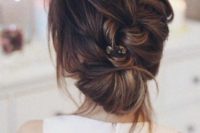 18 a diagonal braided low bun with bangs and a rhinestone hairpiece for a chic modern touch