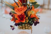 19 a pineapple wedding centerpiece wih orange, red and yellow blooms and some greenery
