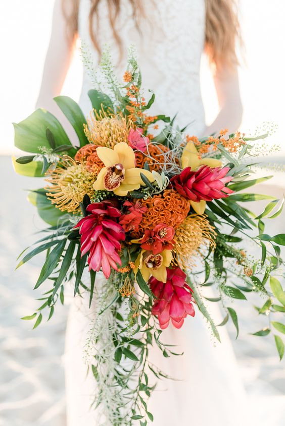 a super bold tropical wedding bouquet with yellow orchids, a cascade and much greenery for a bold and vibrant statement