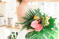 19 an oversized wedding bouquet with pink and yellow blooms and oversized tropical leaves