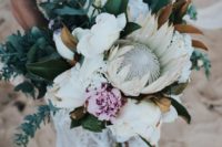 20 a lush wedding bouquet with a king protea, greenery, blush blooms and magnolia leaves for a tropical bride