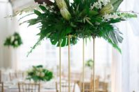 20 a tall centerpiece on a gilded stand with lush greenery, white blooms and king proteas