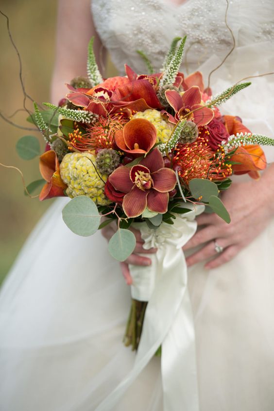 a textural fall bouquet with rust, mauve and orange blooms plus greenery, orchids make it special