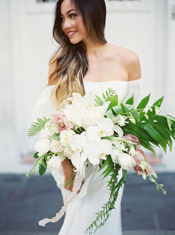 a chic cascading bouquet with white and light pink orchids and greenery for a romantic feel